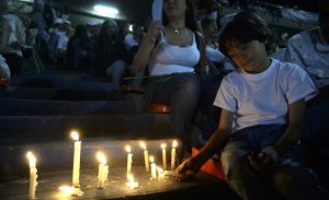 Criança acende velas para vítimas (Foto: RAUL ARBOLEDA / STR / AFP) 